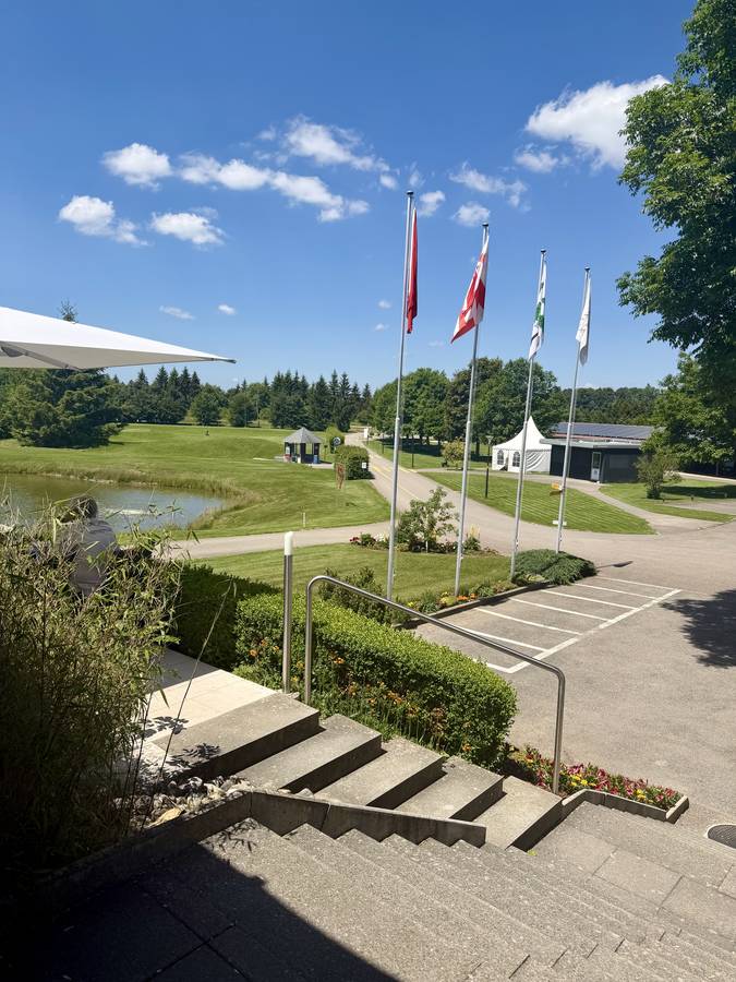 Clubhaus mit Flaggen und Blick über den Platz, Golf-Club Les Bois