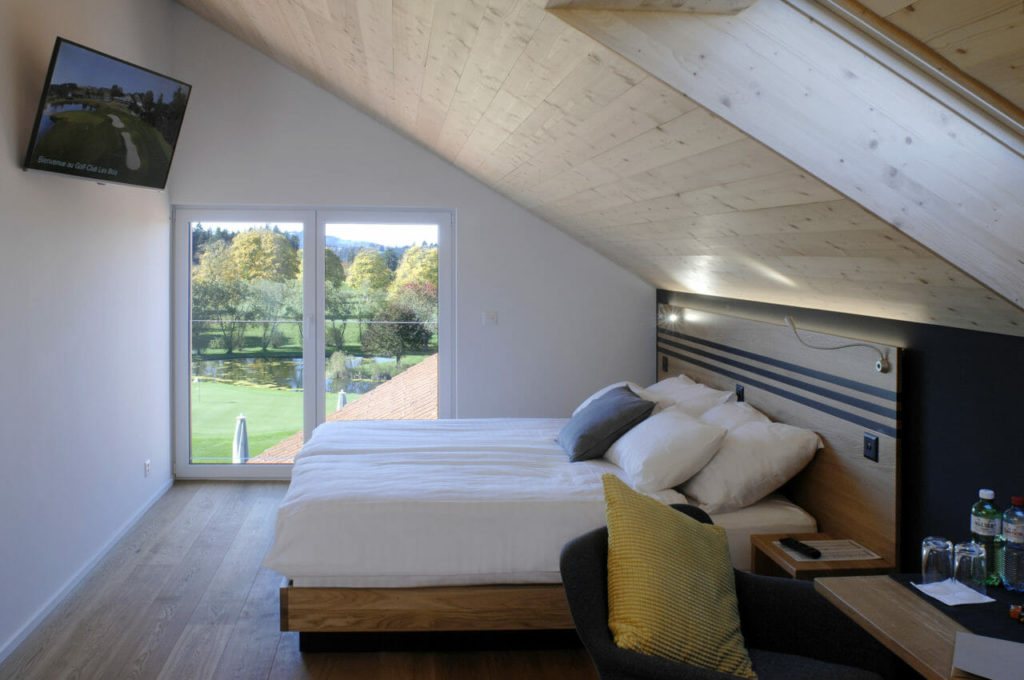 Hotelzimmer im Golf-Club Les Bois mit grossem Fenster und Blick über den Platz